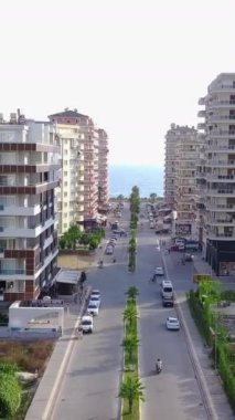 Denize çıkan şehir yolunun üst manzarası. Şarjör. Şehrin yüksek binalarının arasından geçen yol ufukta denize çıkar. Kasaba otellerinin deniz manzaralı düz yol manzarası.