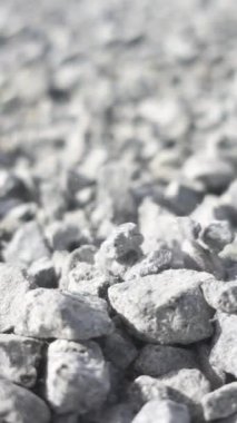 Parlak güneşin altındaki gri granit çakıl taşlarının arka planı. Stok görüntüleri. Beyaz taşların yere düşüşünü kapat, çakıl taşı dokusu..