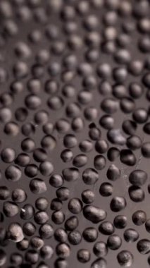 Karabiber arka planda, cam yüzeyinde tahıllar var. Stok görüntüleri. Doku, organik gıda, sağlıklı yaşam tarzı ve diyet konsepti olarak kara biber tohumlarını kapatın..