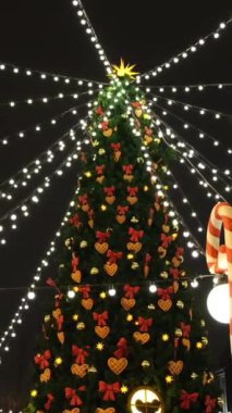 Renkli süslemeleri ve meydanda duran beyaz ışık çelengi ile güzel Noel ağacının altından bakın. Kavram. Noel tatilinin güzel, karlı kış manzarası