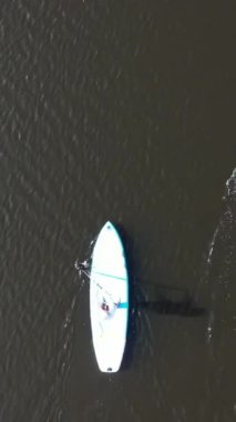 Güneşli bir günde sakin bir nehirde SUP tahtasının üzerinde ceketli tanımlanamayan insanların hava görüntüsü. Su turizmi, sağlıklı yaşam tarzı ve eğlence anlayışı
