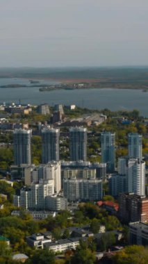 Göl ve yeşil ormanın arka planında yüksek binaları olan bir şehir. Stok görüntüleri. Göl ve orman ufku olan güzel yeşil şehirde modern binalar. Modern şehrin en iyi manzarası...