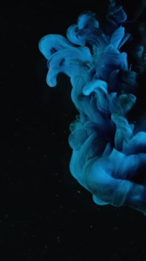 Mavi boya damlaları yavaş çekimde suya karışıyor. Stok görüntüleri. Su altından düzgün mürekkep akıyor ve sıçrıyor. Siyah arkaplanda mürekkep bulutu bırakıyor..