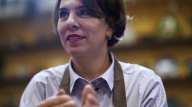 Etrafı esnaf eşyalarıyla çevrili, rahat bir kafede sohbet eden bir kadın. Menkul Kıymetler