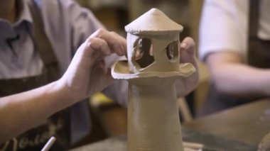 An artisan shapes a detailed clay lighthouse model, showcasing impressive pottery techniques and craftsmanship. Stock Clip