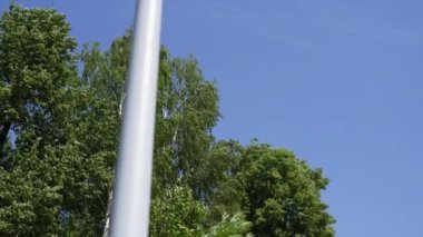 Bu aydınlık ve güneşli günde, açık mavi gökyüzünün altındaki yemyeşil ağaçların yanında duran büyüleyici bir sokak lambası. Kırp