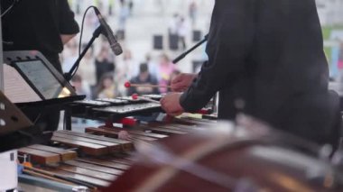 Bir müzisyen ksilofonda ustaca performans sergiliyor, dinleyiciyi çekici ve canlı müzikle cezbediyor. Kırp