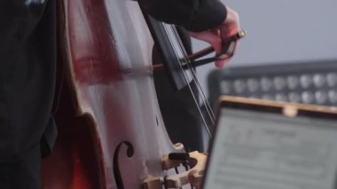 Çelloyu ustalıkla çalan bir müzisyeni yakindan çekerek ustalıkla çelloyu ustalıkla çalmak, ustalığını ön plana çıkarmak. Kırp