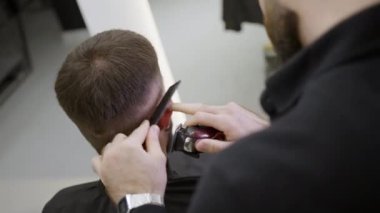 Yetenekli bir berber, modern bir kuaför salonunda çalışırken müşterinin saçını ustalıkla şekillendirir. Kırp