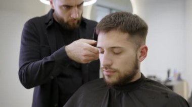 Şu anda modern, şık bir berber dükkanında bir adamın saç stilini titizlikle şekillendiren yetenekli bir berber. Kırp