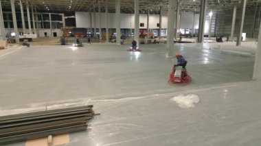 Şu anda inşaat halinde olan büyük bir depo, işçiler özenle beton döşemeyi bitiriyor. Kırp