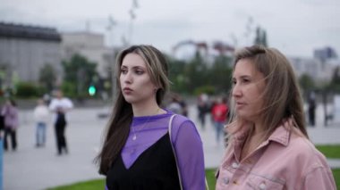 Gürcistan, Tiflis - 20 Temmuz 2024: Kasvetli ve kasvetli bir günde, iki kadın bir şehir parkında canlı şehir yaşamını sergilemek için bir araya gelir. Kırp