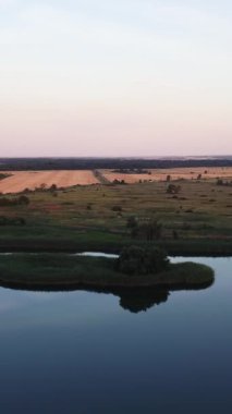 Altın hasat mevsiminde sıcak güneş ışığıyla yıkanan güzel tarım arazilerinin hava manzarası. Güzel, sakin bir nehir ve çayırlar..