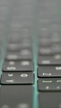 Laptopun yan görüntüsü ya da bilgisayar detayları, beyaz sembollü siyah klavye. Kamera odaklı arka planda ışıklandırılmış klavyenin aşırı yakınlaşması.