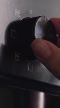 Evdeki mutfakta kadın elinin fırın sapını döndürmesine yakın çekim. Kolay pişirme için mutfak gereçleri.