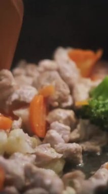 Kızartma tavasında sebzeli tavuk pişirmek. Karıştırma ve haşlama sebze ve ete yakın ahşap gıda çevirici, sağlıklı beslenme.