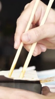 Çubuklu sebzeli şehriye yeme manzarası. Vejetaryen Asya yemeği yiyen, karton kutudan baharatlı soslu tavada makarna yiyen adama yakın çekim..