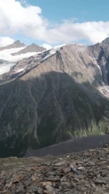 Uçsuz bucaksız karlı dağ sırasının tepesinden bak. Şarjör. Büyük dağların üzerinde süzülen bulutlarla nefes kesici vahşi doğa.