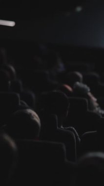 İnsanlar karanlık salonda oturup film izliyorlar. Video kaydı. Sinema salonundaki insanların bir filmi dikkatle izlemesi, boş zaman kavramı.