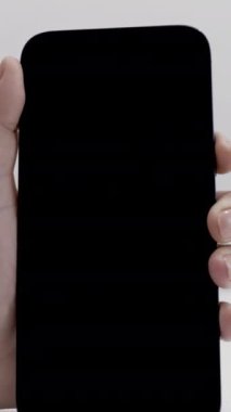 Beyaz arka planda izole edilmiş yeni ve güzel bir akıllı telefonu aktif hale getiren kadın eline yakın çekim. Modern teknolojiler kavramı, ilk kez yeni bir cihaz açılıyor..