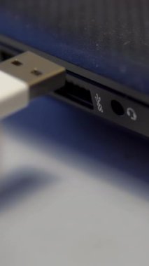 Beyaz arka planda izole edilmiş dizüstü bilgisayara beyaz USB kablosu yerleştiriliyor. Cihazı kablosu olan bir bilgisayara bağlamayı kapat.