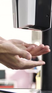 Otomatik alkol dezenfektanı ile ellerini yıka. Temassız oto dezenfektan cihazıyla el spreyi, koronavirüs salgını sırasında kişisel koruma..