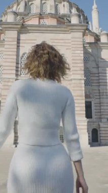 Güzel bir kadın camiye gider. Başla. Cami önünde yürüyen güzel bir kadının arka görüntüsü. İstanbul 'da güneşli bir günde camiye çekici bir kadın giriyor..