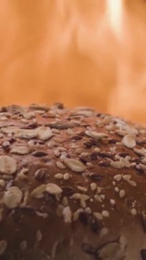 Ateşin arka planında çörek. Stok görüntüleri. Hamburgerler için tahıl ekmeği ateşte kızartılır. Loaf ızgarada ateşte pişiyor. Barbekü ızgarasında Burger pişiriyorum. Izgaradaki cehennem gibi..