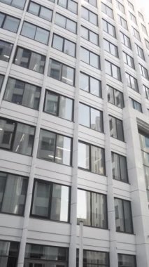 Şehir işindeki bir diktatörün düşük açılı görüntüsü. Birçok penceresi ve beyaz cepheli, mimari konsepti olan güzel, modern bir ofis binası olan bir sokak..