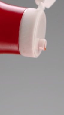 Ketçap şişeden çıkarılıyor. Stok görüntüleri. Gri arka planda kırmızı ketçap jeti yakın plan. Ketçap büyük kırmızı şişeden dökülür..