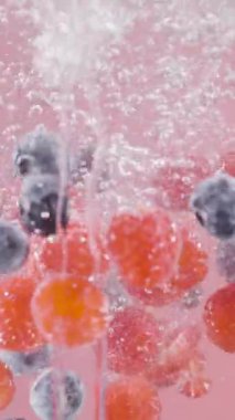 Çilekler izole arka planda suya düşer. Başla. Meyveler kabarcıklarla suya düşer. Hafif arkaplandaki dutların ferahlatıcı düşüşü.