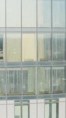Arka plandaki yüksek binaların pencereleri. Stok görüntüleri. Güneşli bir günde şehrin arka planında gökdelenlerin panoramik pencerelerinin üst görüntüsü. Kuşların yüksekliğinde gökdelenlerin güzel pencereleri