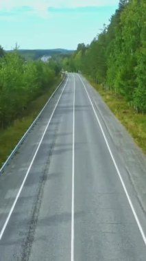 İskandinav köknar ormanının üzerinde uçmak, köy yolundan geçmek. Görüntü. Boş yol ve yaz ormanının havadan görünüşü