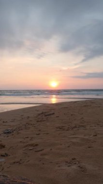 Gün batımında uzun deniz dalgaları olan güzel bir kum. Başla. Bulutlarla birlikte denizde sakin bir gün batımı. Yazılı sahilden deniz ufkunda bulutlu gün batımı.