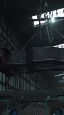 Fabrikadaki süspansiyonlar hakkında geniş bir metal parçasının düşük açılı görüntüsü. Şarjör. Fabrikada yük taşımak için çapaları olan askıya alma sistemleri