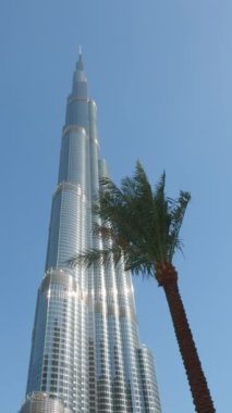 Burç Halife Dubai şehrinde, Birleşik Arap Emirlikleri. Başla. Dev bir gökdelen ve palmiye ağaçlarının alçak açılı görüntüsü