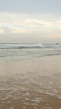 Uzun dalgaları ve mavi bulutlu gökyüzü olan güzel kumlu bir sahil manzarası. Başla. Tropikal adasında güzel sakin bir sahil