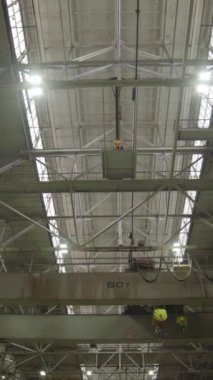 Geniş bir deponun geniş bir görüntüsü. Birden fazla vinç ve parlak, etkili endüstriyel ışıklandırma var. Menkul Kıymetler