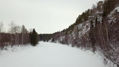 A serene and tranquil winter scene beautifully showcasing a snow covered path framed by majestic cliffs and tall trees. Stock Clip