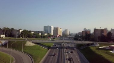 Pürüzsüz, modern mimariyle çevrili, açık mavi bir gökyüzü altında hareketli bir şehir otoyolunun geniş bir hava manzarası. Menkul Kıymetler