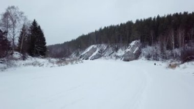 Huzurlu ve sakin bir kış sahnesinde karla kaplı nehir kıyısı ve yemyeşil ağaçlar derin huzuru çağrıştırıyor. Menkul Kıymetler