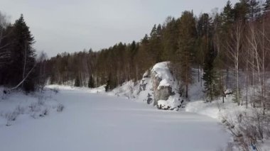 A peaceful and serene winter scene showcasing a snowy river that is beautifully surrounded by evergreen trees. Stock Clip