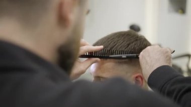 Çok yetenekli bir berber, saçlarını ustalıkla şekillendirir, dikkat çekici bir hassasiyet ve her detaya dikkat çeker. Kırp