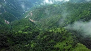 Nefes kesici bir hava manzarası, yemyeşil dağlar ve bulutlu gökyüzünün altında yoğun, canlı ormanlar sergiliyor. Menkul Kıymetler