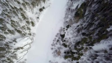 Hava manzarası, kışın dingin güzelliğinde engin ve yoğun bir ormanın içinde kıvrılan karla kaplı bir nehri gösteriyor. Menkul Kıymetler