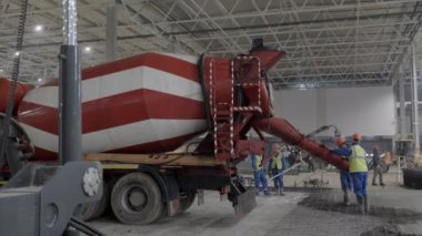 İnşaat işçileri ve beton karıştırıcı kamyonu temele taze beton döken bir alanda çalışıyor. Kırp