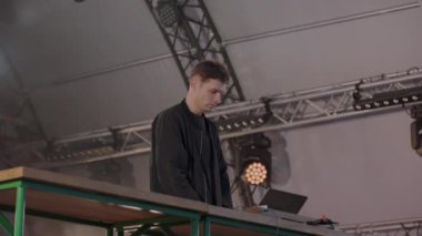 Heyecan verici bir DJ seti canlı bir festival çadırında, hareketli ışıklandırması ve dinamik, daldırıcı bir atmosferi olan bir yerde geçiyor. Kırp