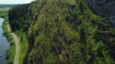 Sakin bir nehrin kenarındaki canlı kayalık manzaraların nefes kesen manzaralarının tadını çıkar. Doğanın güzelliğini vurgula. Kırp
