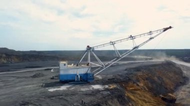 Geniş bir açık çukur mayın alanında özenle çalışan büyük bir kazıcıyı güzelce gösteren bir hava manzarası. Menkul Kıymetler