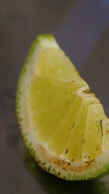 Çarpıcı bir video siyah bir yüzey üzerinde bir dilim kireç sergiliyor. Yakıldıkça, kireç aromatik yağlar yayar ve dinamik bir sahne yaratır.